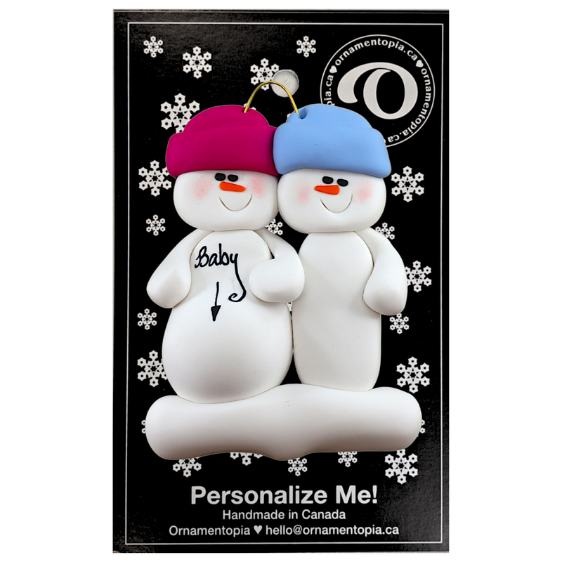 Family ornament with 2 snowmen in bright hats, one pregnant, on display backing card.