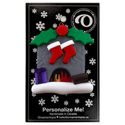 Vibrant fireplace ornament with holly and Christmas presents, displaying 2 red stockings, on display backing card.