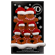 Family ornament with 7 brown gingerbread figures in red Christmas hats, on display backing card.