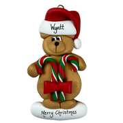 Tan bear in red festive hat holding two candy canes ornament, personalized with name.