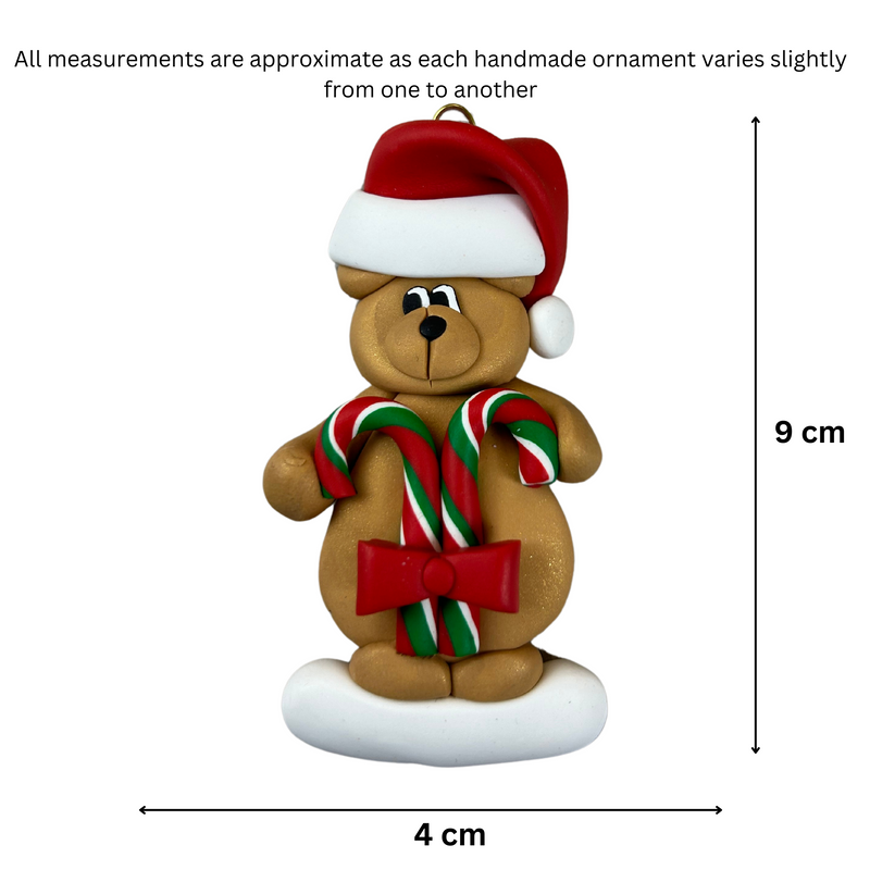 Tan bear in red festive hat holding two candy canes ornament, graphed to show size (4x9cm).
