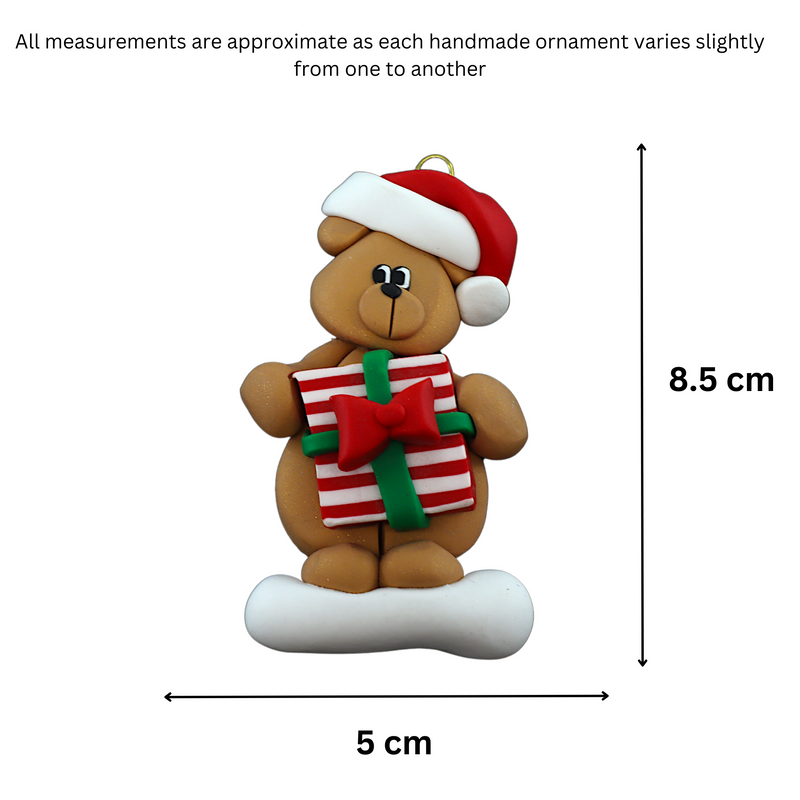 Tan bear in red festive hat holding colourful present ornament, graphed to show size (5x8.5cm).
