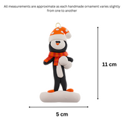 Penguin wearing orange hat and scarf ornament, graphed to show size (5x11cm).