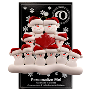 Family ornament with 10 white snowmen in red hats, gathered around a red maple leaf, on display backing card.