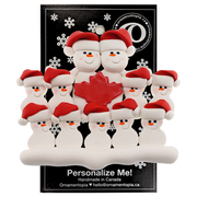 Family ornament with 11 white snowmen in red hats, gathered around a red maple leaf, on display backing card.