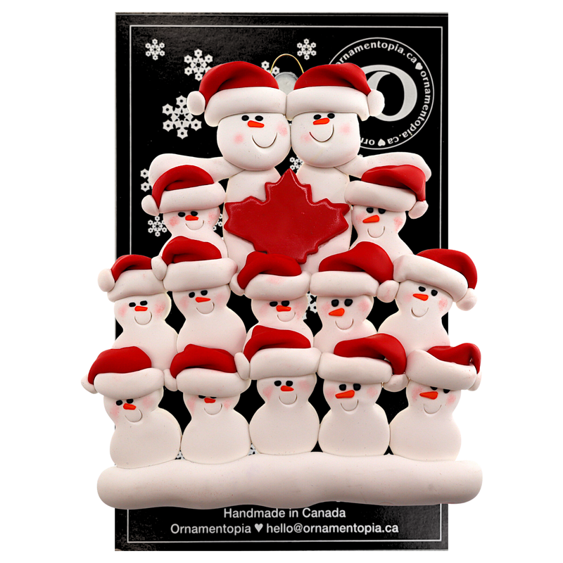 Family ornament with 14 white snowmen in red hats, gathered around a red maple leaf, on display backing card.