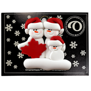 Family ornament with 3 white snowmen in red hats, gathered around a red maple leaf, on display backing card.