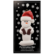 Ornament of white snowman in red hat holding two chocolate bars, on display backing card.