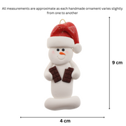Ornament of white snowman in red hat holding two chocolate bars, graphed to show size (4x9cm).