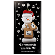 Ornament of white snowman in red hat holding several parcels, on display backing card.
