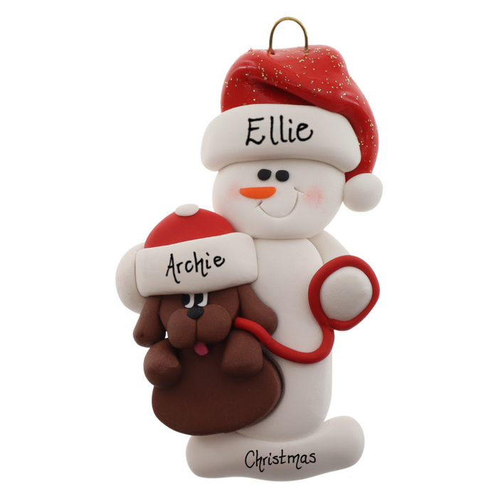 Ornament of white snowman in red hat holding a brown dog on a leash, personalized with name.