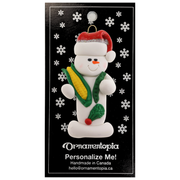Ornament of white snowman in red hat holding various colourful vegetables, on display backing card.