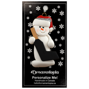 Ornament of white snowman in red hat holding a goalie stick, on display backing card.