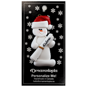Ornament of white snowman in red hat holding a white diploma, on display backing card.