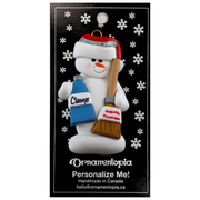 Ornament of white snowman in red hat holding a broom and bottle of cleaning solution, on display backing card.