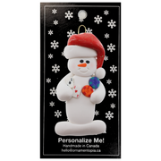 Ornament of white snowman in red hat holding cards and poker chips, on display backing card.