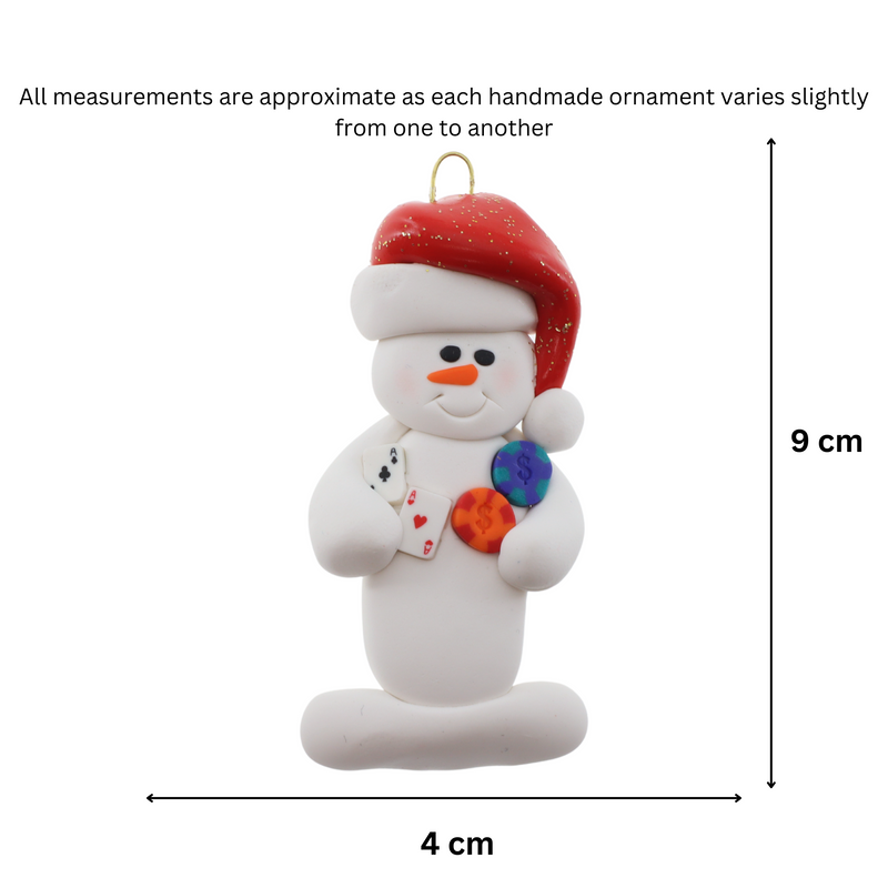 Ornament of white snowman in red hat holding cards and poker chips, graphed to show size (4x9cm).