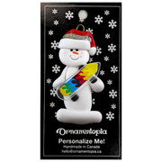 Ornament of white snowman in red hat holding a vibrant skateboard, on display backing card.