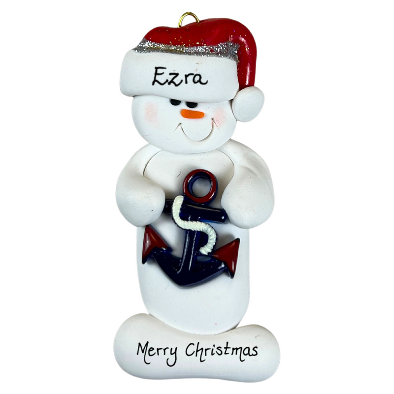 Ornament of white snowman in red hat holding a plastic anchor, personalized with name.