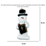 Ornament of white snowman in black top hat, holding a Bible, graphed to show size (4x9cm).