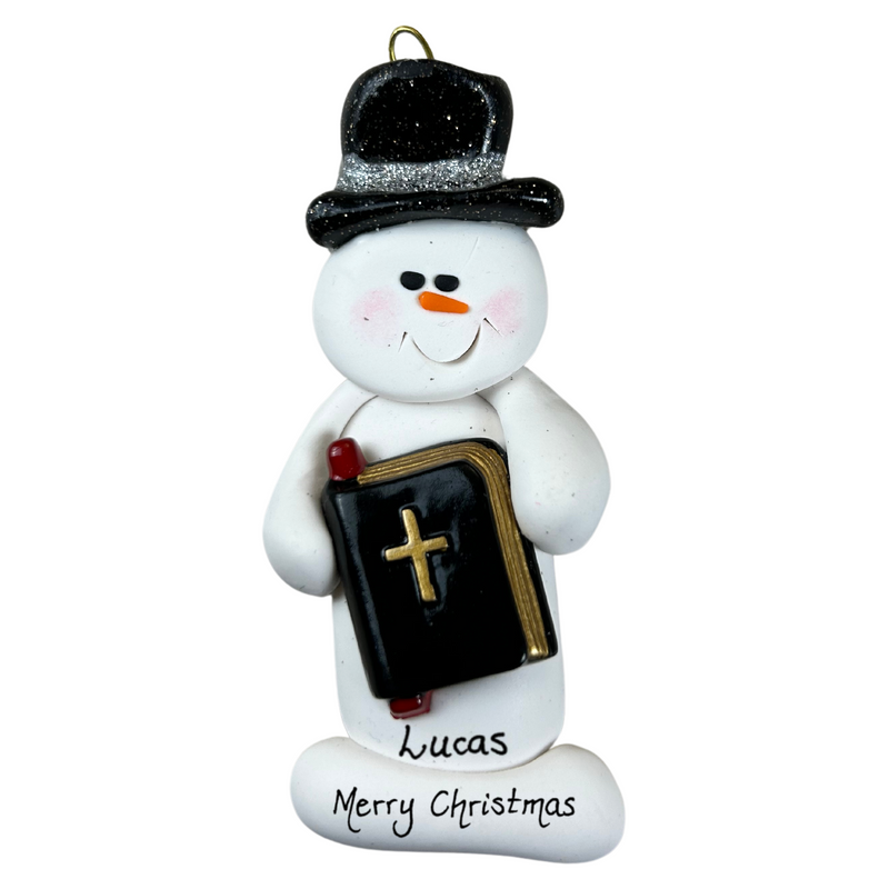 Ornament of white snowman in black top hat, holding a Bible, personalized with name.