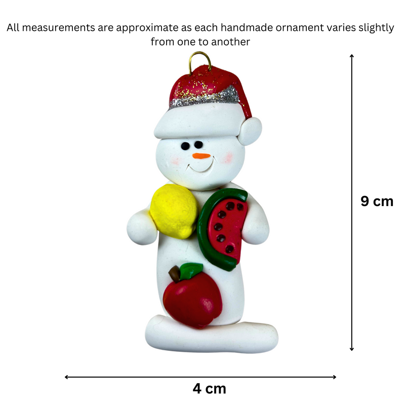 Ornament of white snowman in red hat holding various fruits, graphed to show size (4x9cm).