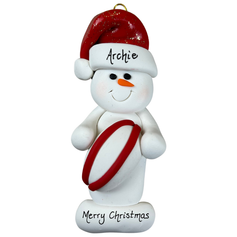 Ornament of white snowman in red hat holding a red and white rugby ball, personalized with name.