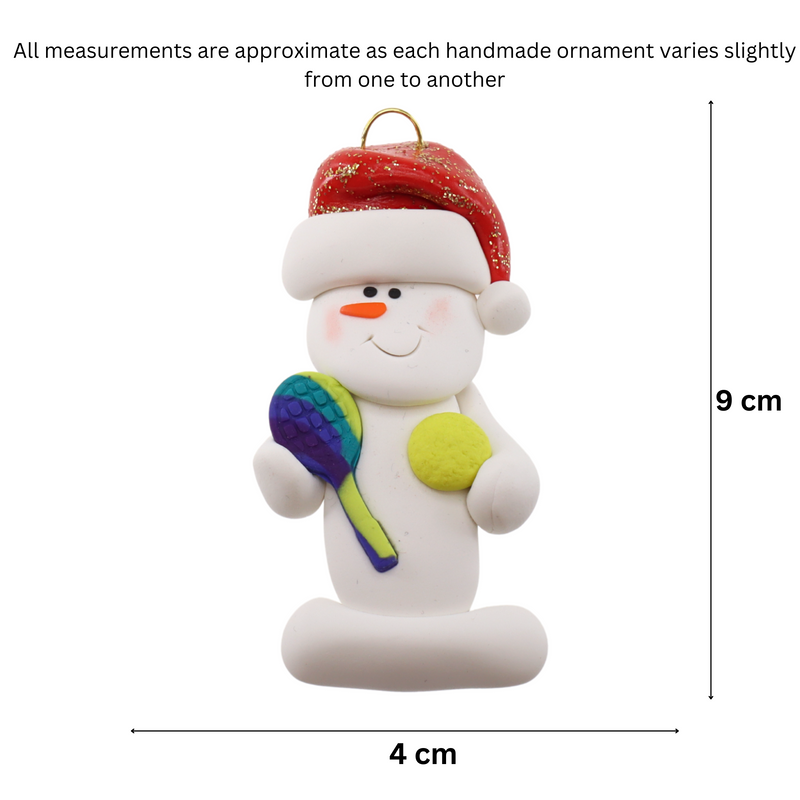 Ornament of white snowman in red hat holding a tennis paddle and ball, graphed to show size (4x9cm).