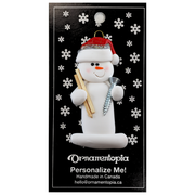 Ornament of white snowman in red hat holding a piece of wood and a screw, on display backing card.