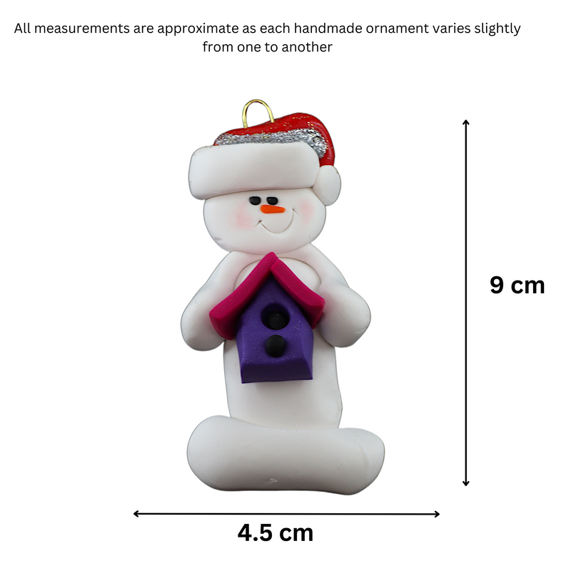 Ornament of white snowman in red hat holding a pink and purple birdhouse, graphed to show size (4.5x9cm).