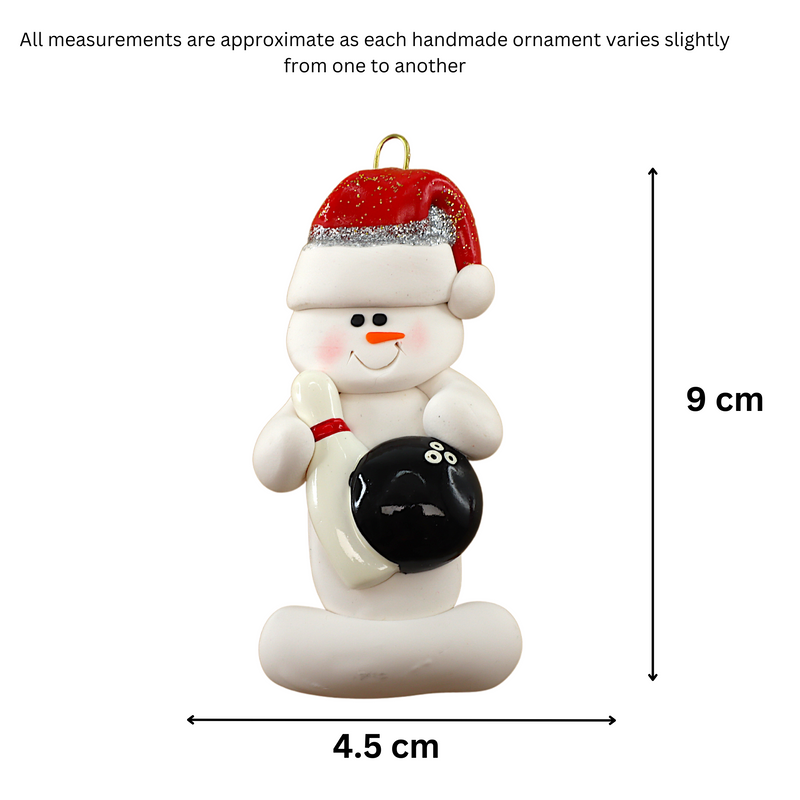 Ornament of white snowman in red hat holding a black bowling ball and pin, graphed to show size (4.5x9cm).