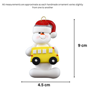 Ornament of white snowman in red hat holding a yellow school bus, graphed to show size (4.5x9cm).