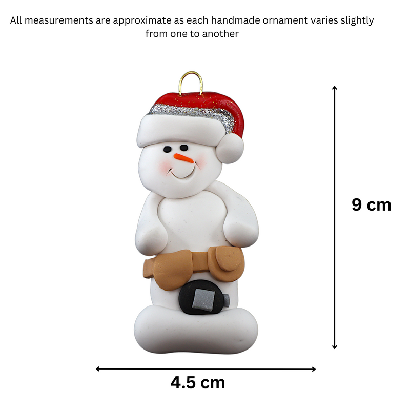 Ornament of white snowman in red hat wearing tool belt with tape measure, graphed to show size (4.5x9cm).