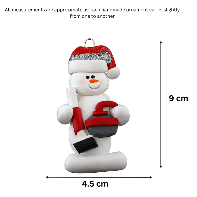 Ornament of white snowman in red hat holding red curling stone and broom, graphed to show size (4.5x9cm).