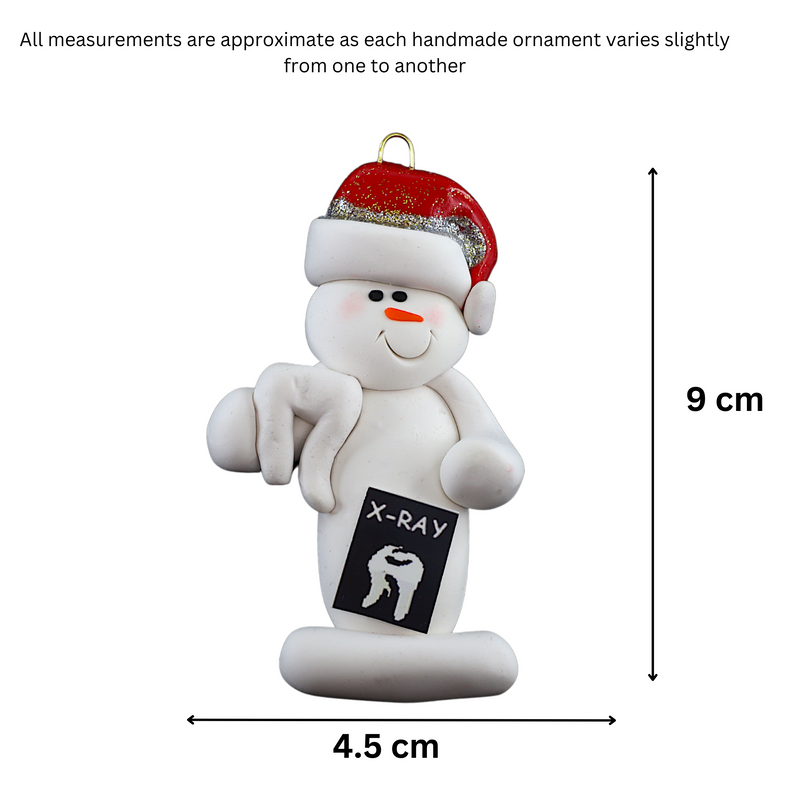 Ornament of white snowman in red hat holding dental x-ray and white tooth, graphed to show size (4.5x9cm).