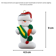 Ornament of white snowman in red hat holding various colourful vegetables, graphed to show size (4.5x9cm).