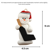 Ornament of white snowman in red hat holding a goalie stick, graphed to show size (4.5x9cm).