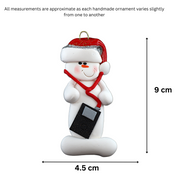 Ornament of white snowman in red hat holding an i-pod with headphones, graphed to show size (4.5x9cm).