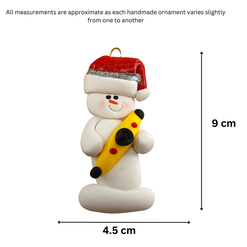 Ornament of white snowman in red hat holding a yellow kayak, graphed to show size (4.5x9cm).