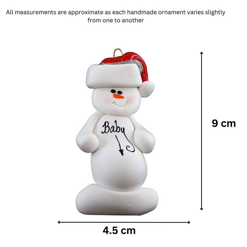 Ornament of white snowman in red hat with a round stomach that says “baby”, graphed to show size (4.5x9cm).
