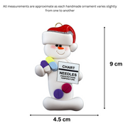 Ornament of white snowman in red hat holding various medications and a medical chart, graphed to show size (4.5x9cm).