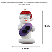 Ornament of white snowman in red hat holding a vibrant snowboard, graphed to show size (4.5x9cm).