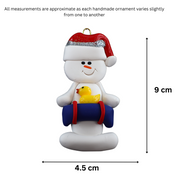 Ornament of white snowman in red hat holding a blue inflatable tube and yellow duck, graphed to show size (4.5x9cm).