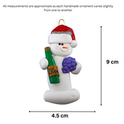 Ornament of white snowman in red hat holding a cluster of grapes and a wine bottle, graphed to show size (4.5x9cm).