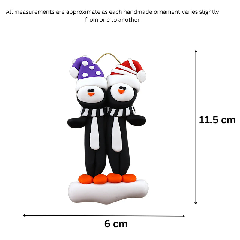 Family ornament with 2 black and white penguins in colourful festive hats, graphed to show size (6x11.5cm).