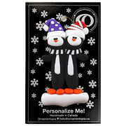 Family ornament with 2 black and white penguins in colourful festive hats, on display backing card.