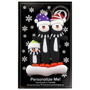 Family ornament with 3 black and white penguins in colourful festive hats, on display backing card.