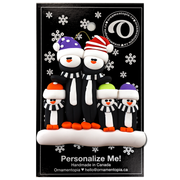 Family ornament with 5 black and white penguins in colourful festive hats, on display backing card.