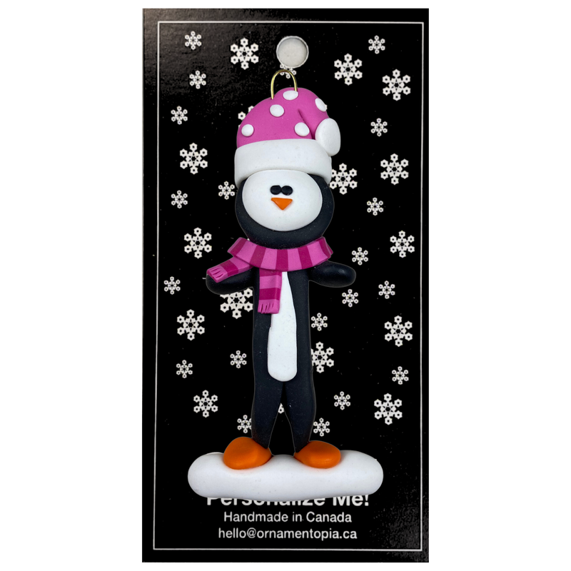 Penguin wearing pink hat and scarf ornament, on display backing card.