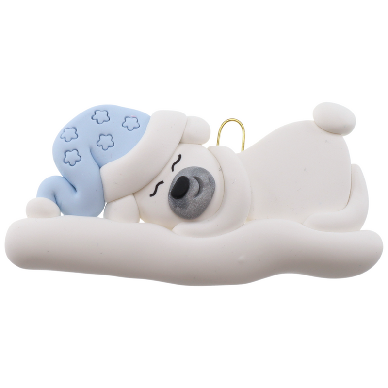 Ornament of white sleeping polar bear baby in a blue hat.